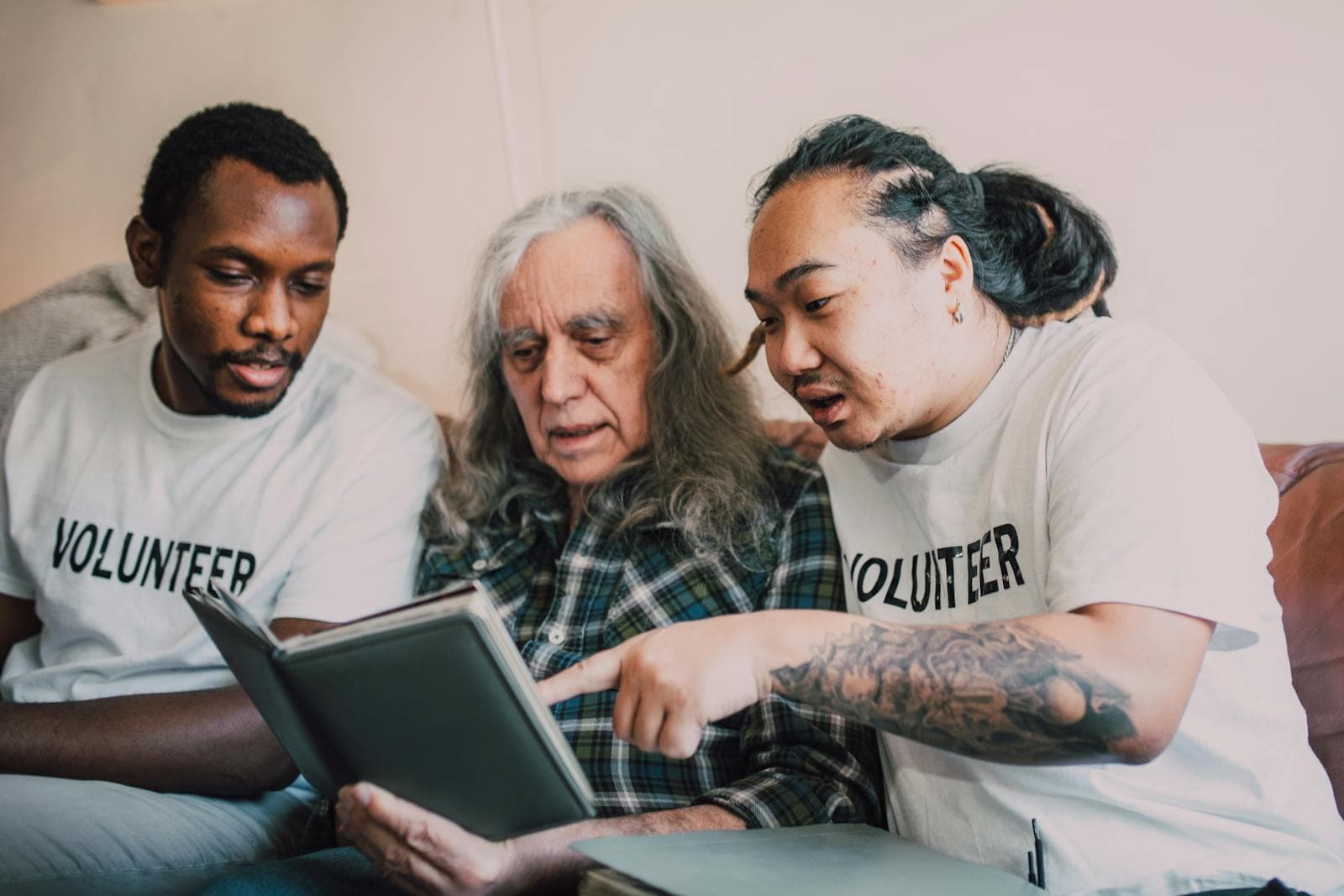 Together As One volunteers sitting with an older man looking at a photo album